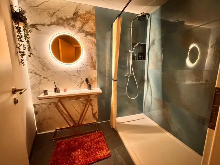 Dusche mit Marmorwand und beleuchtetem Spiegel bei ThaiVital in Basel